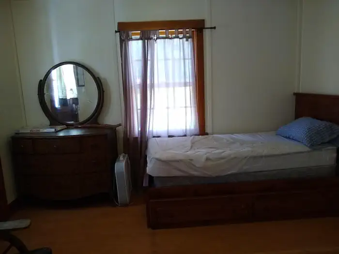 A bed next to a dresser and window.